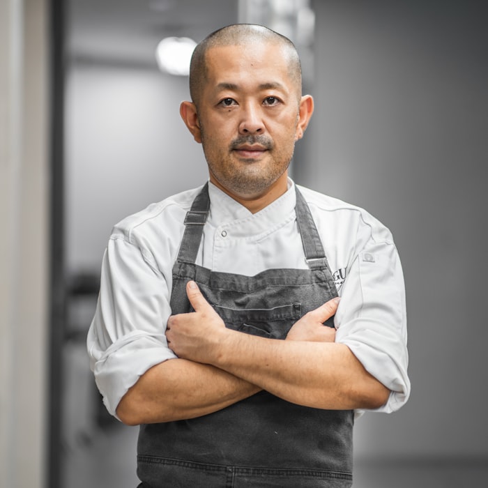 A chef in whites and an apron standing in a restaurant kitchen