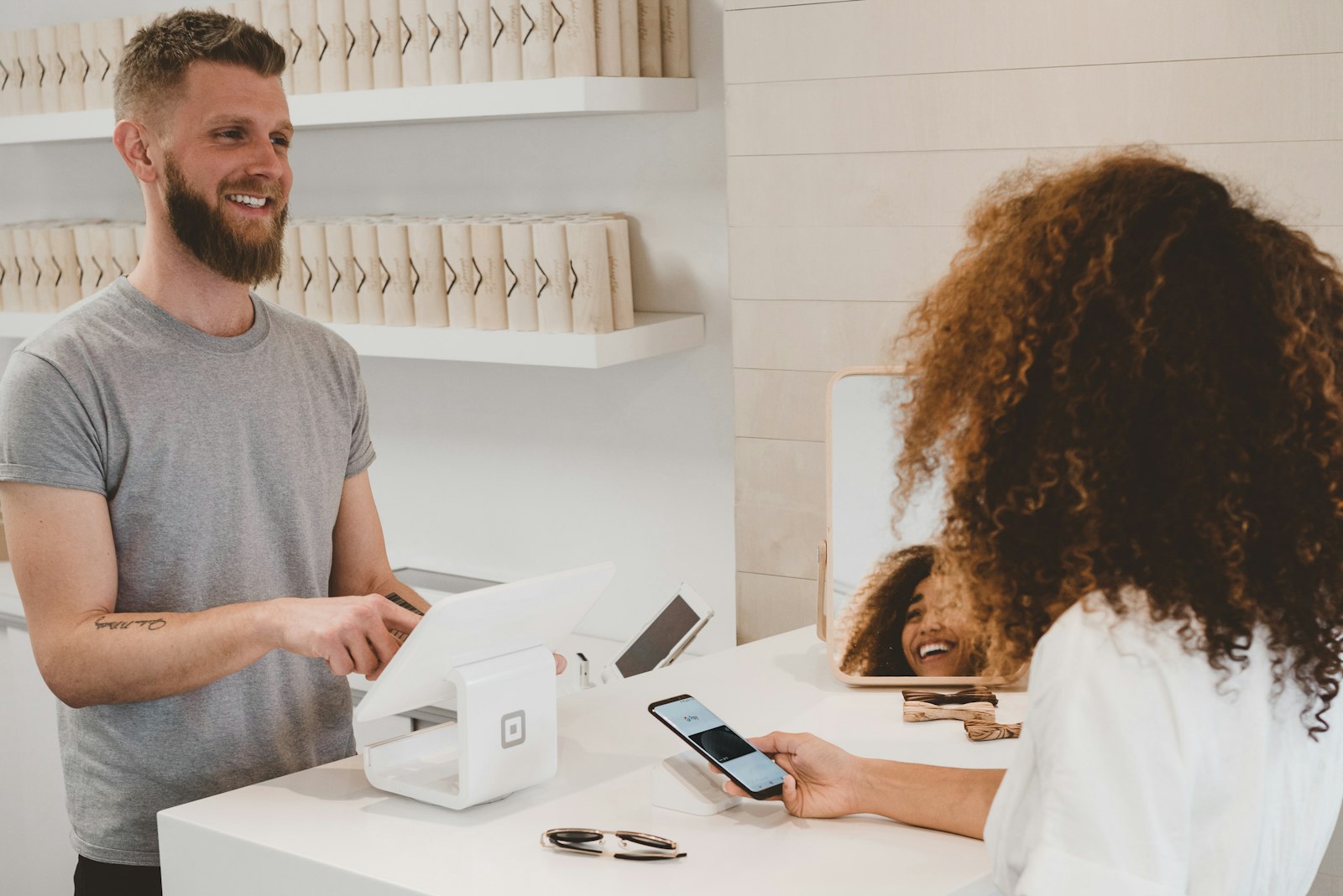 A smiling shop worker helping a customer at the counter